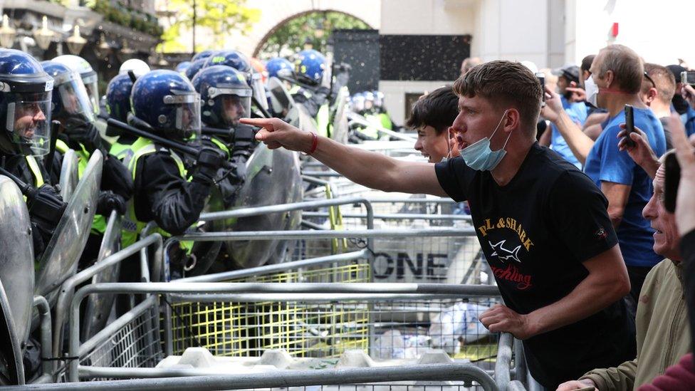 Demonstrators shouting at police across a barrier