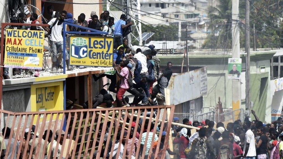 People loot shops in Delmas, a commune near Port-au-Prince, during protests against the rising price of fuel, on July 8, 2018.