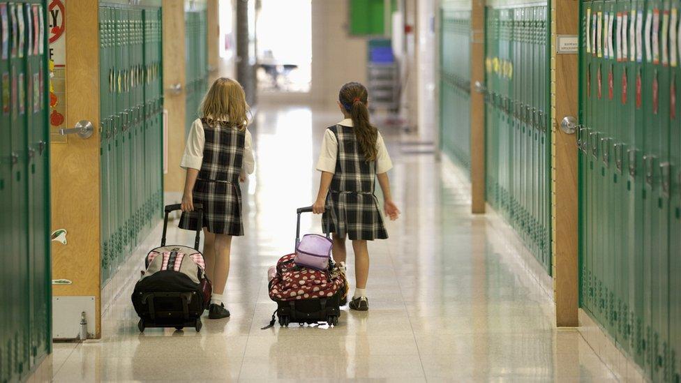 Two girls walk down a school hallway