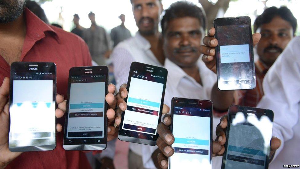 Indian drivers for Uber show mobiles phones given to them by the company