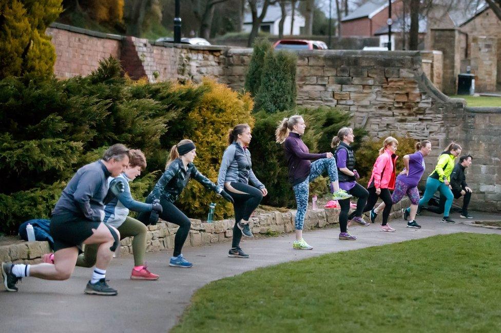 People exercise in a group class in a park