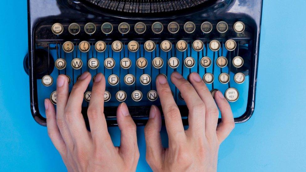 Hands typing on a manual "qwerty" typewriter