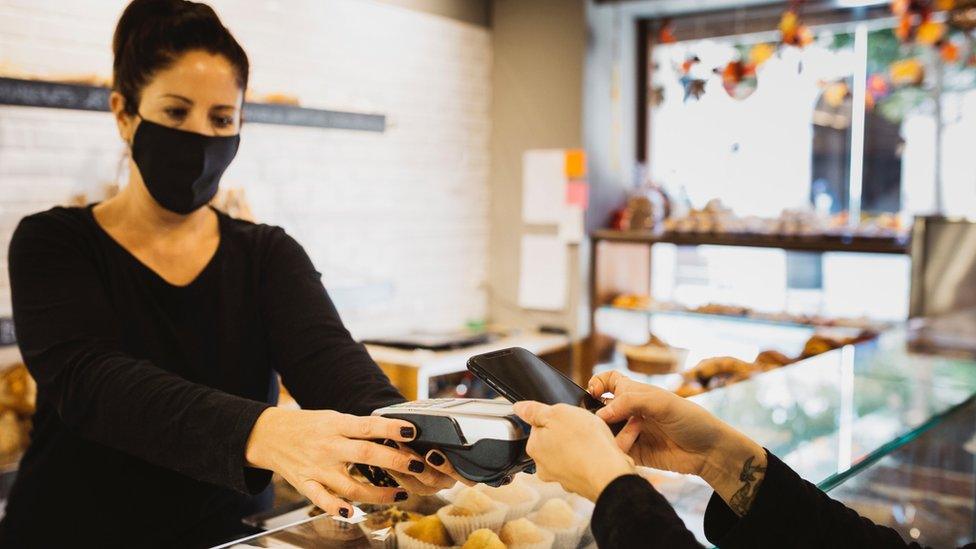 Contactless payment in bakery with staff member in a mask