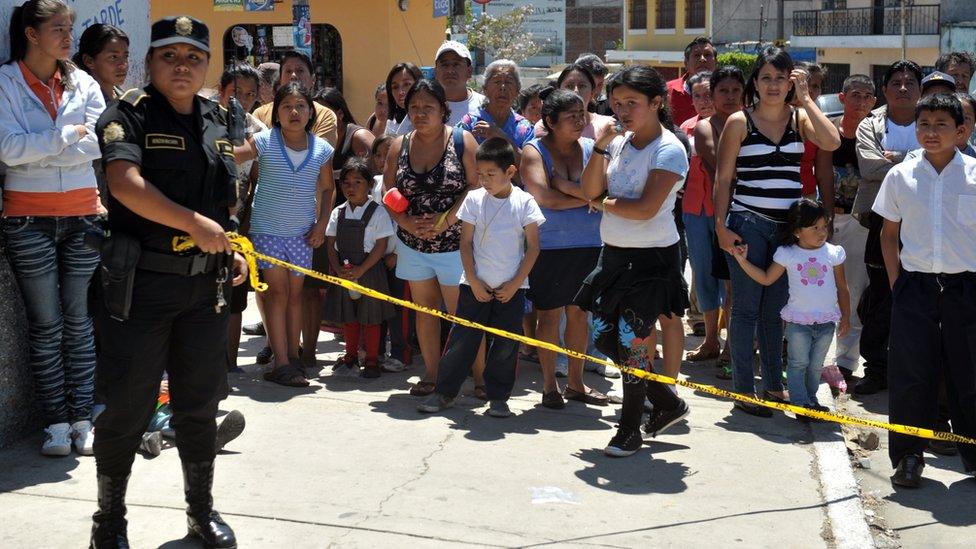 A Guatemalan police officer cordons off the scene of a murder