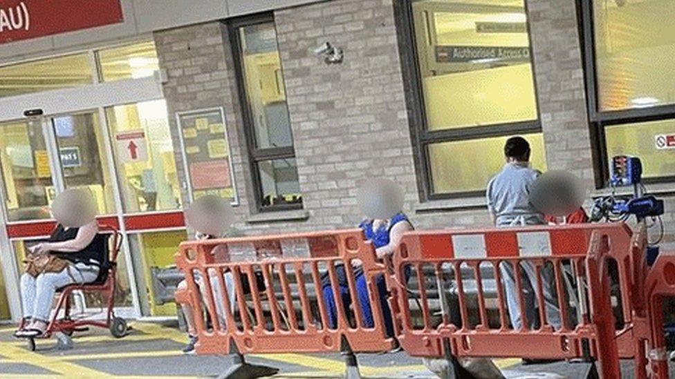 Patients sitting under blankets and a nurse outside accident and emergency at Addenbrooke's Hospital in Cambridge