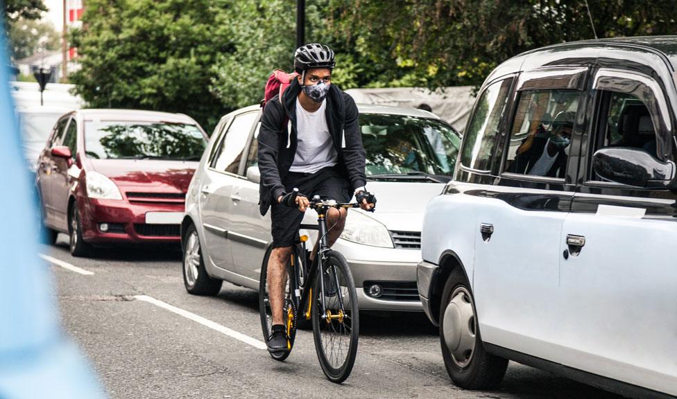 A stock image of a cyclist riding past cars