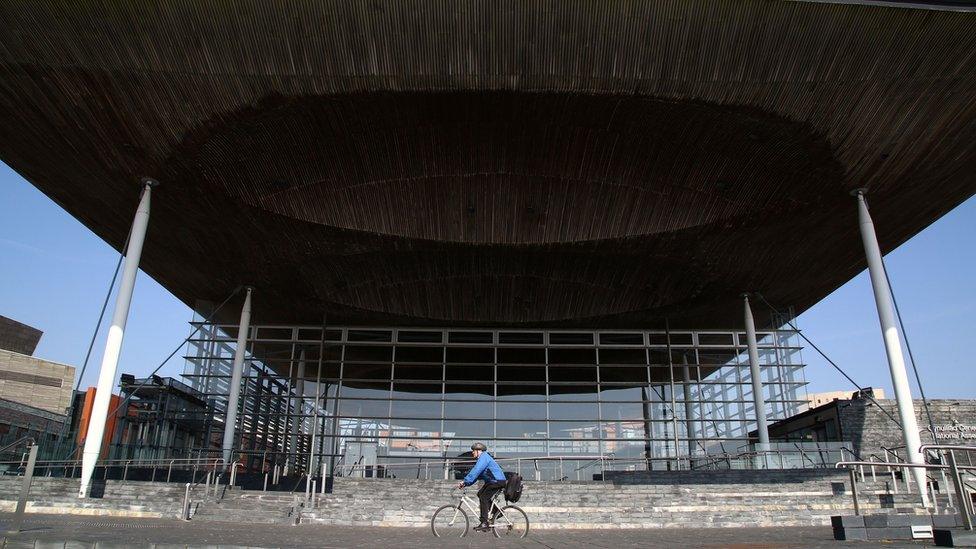 A cyclist riding past the Senedd in Cardiff Bay