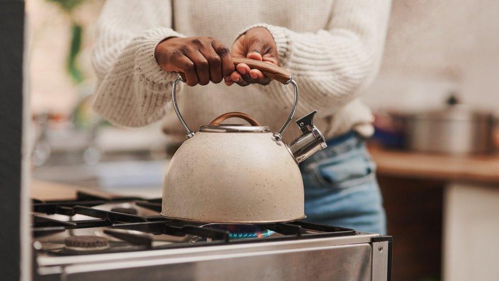 Woman boiling water on a gas stove