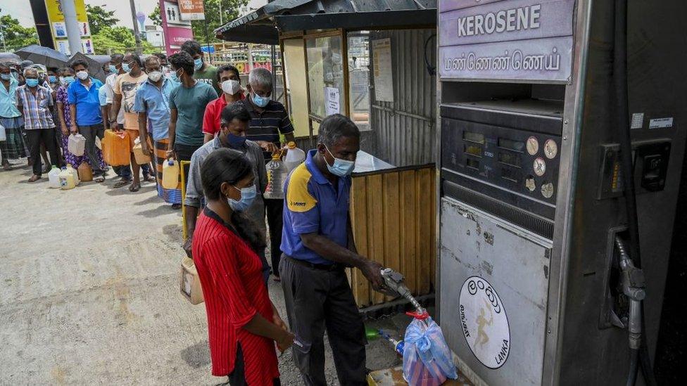 People stand in a queue to buy kerosene oil used in cooking stoves in Colombo on August 31, 2021 following Sri Lanka's declaration of state of emergency over food shortages as private banks ran out of foreign exchange to finance imports.