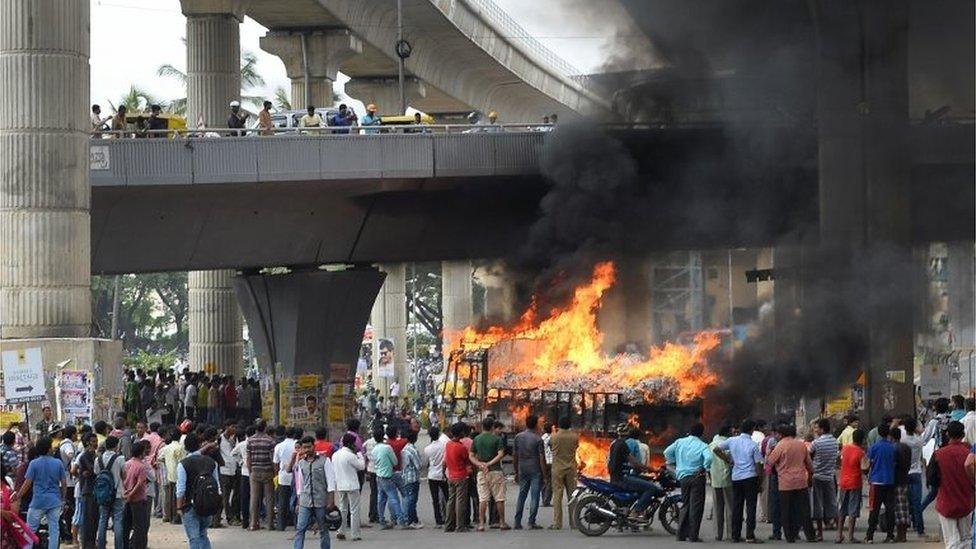 Onlookers watch as a truck from neighbouring state Tamil Nadu burns after it was set alight by agitated pro-Karnataka activists as the Cauvery water dispute erupted following the Supreme Court's order to release water to Tamil Nadu, in Bangalore on September 12, 2016.