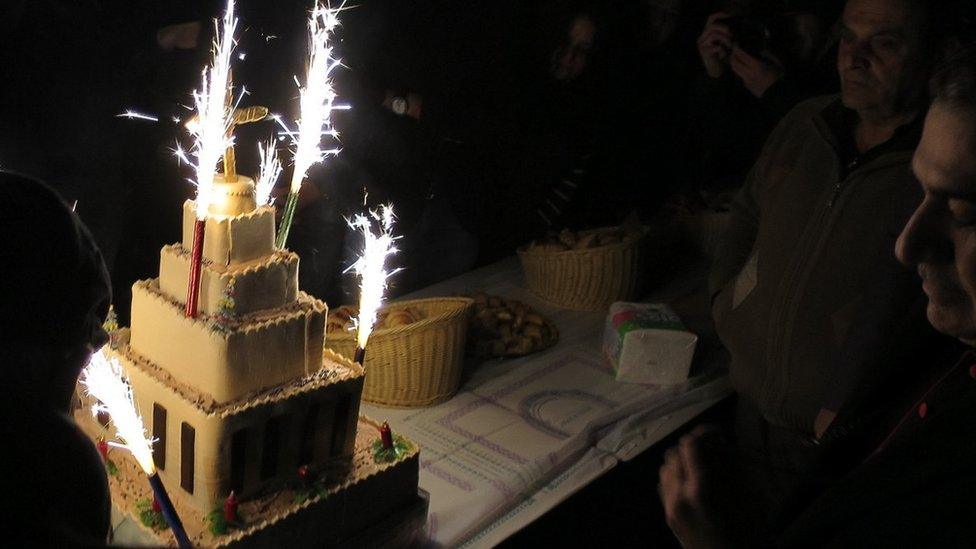 Candles burn on a cake in the shape of the new church