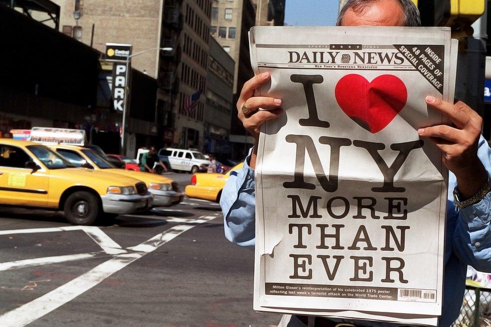 A man reads a copy of the New York Daily News newspaper bearing a poster designed by Malcolm Glaser (19 September 2001)