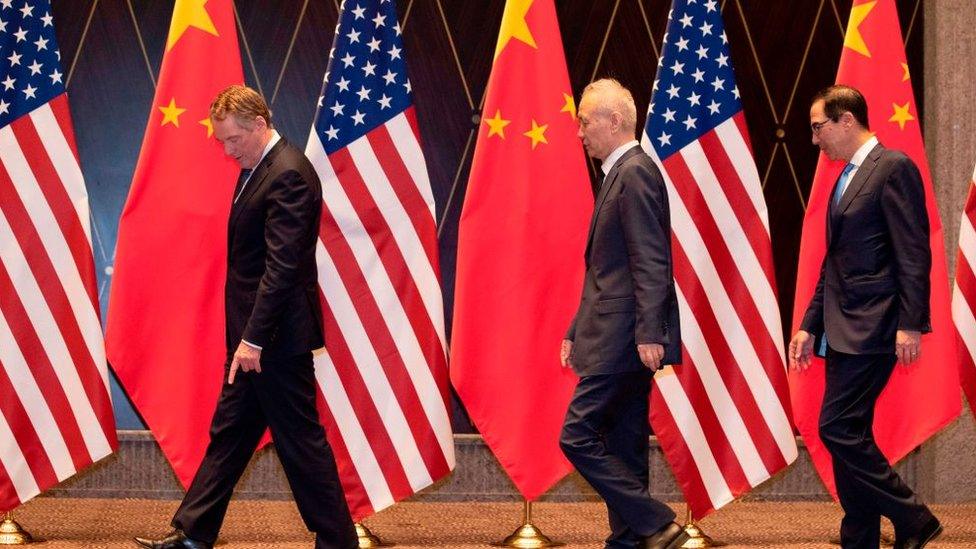 US Trade Representative Robert Lighthizer (L) points at markers on the floor as he leads Chinese Vice Premier Liu (C) and US Treasury Secretary Steven Mnuchin (R) to their positions for a "family photo" at the Xijiao Conference Centre in Shanghai on July 31, 2019