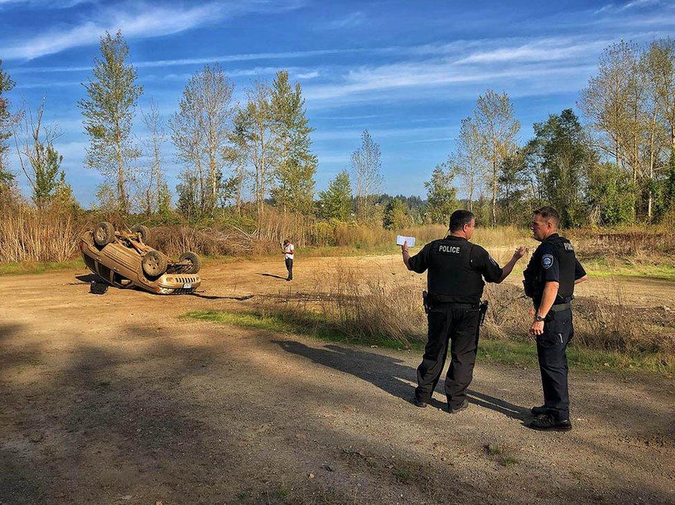 Police stand near an upturned car