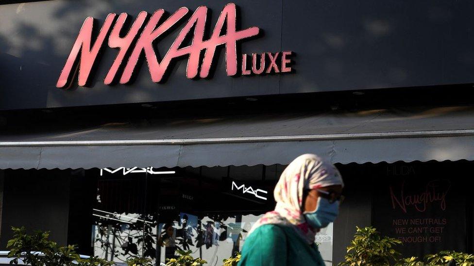 In this picture taken on December 29, 2021, a woman walks past a store for beauty products platform Nykaa in Mumbai.