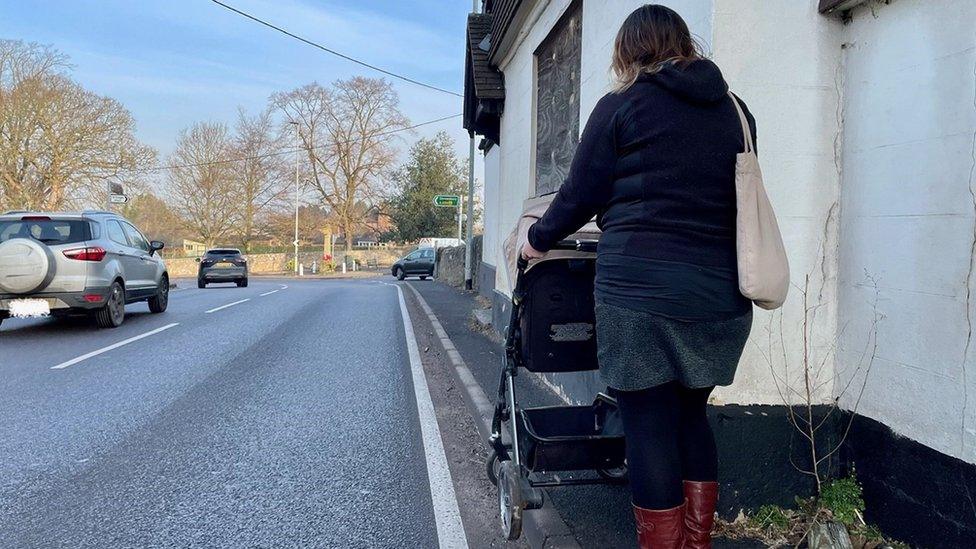 A woman with a pushchair on a narrow pavement