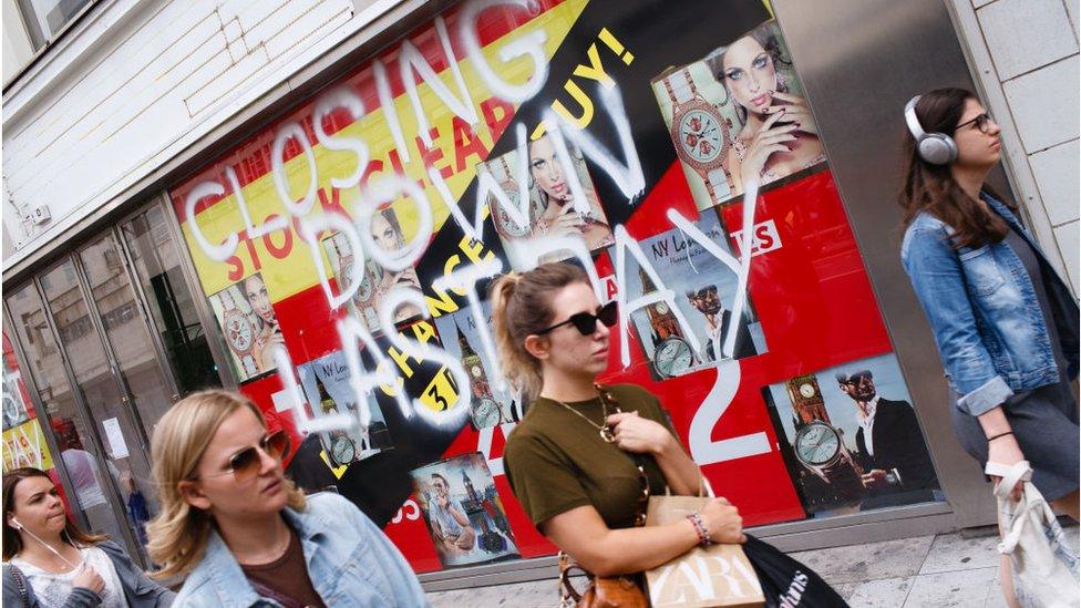 People walk past a closed down store in Oxford Street