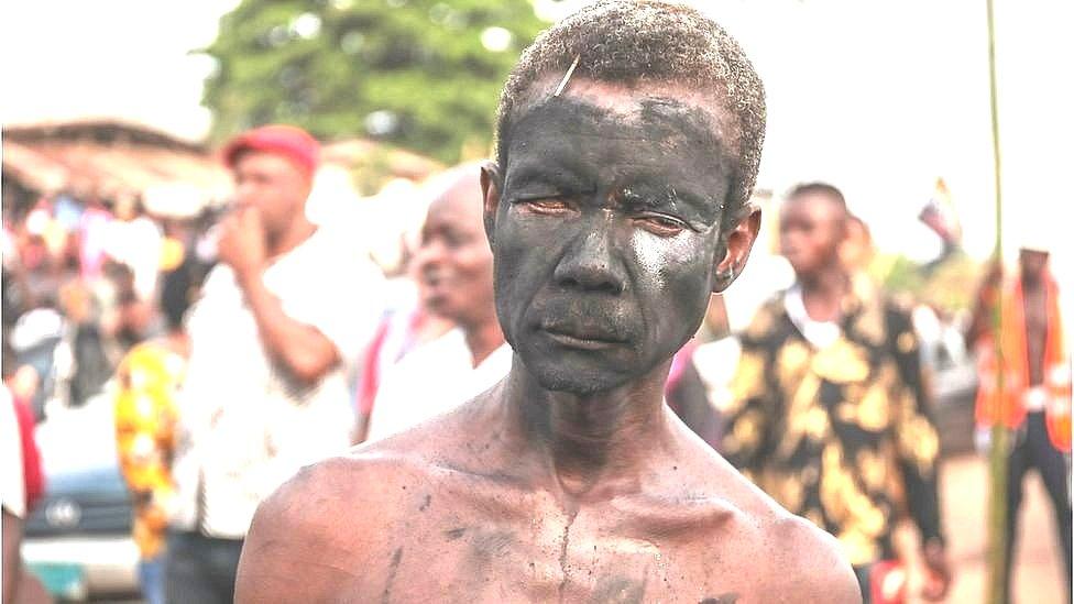 A man with a face painted with charcoal in a street of Arondizuogu during the Ikeji Festival in Nigeria