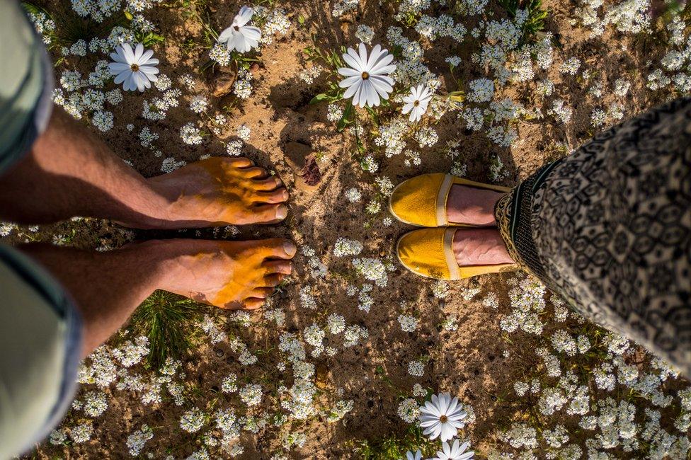 Two pairs of feet surrounded by flowers