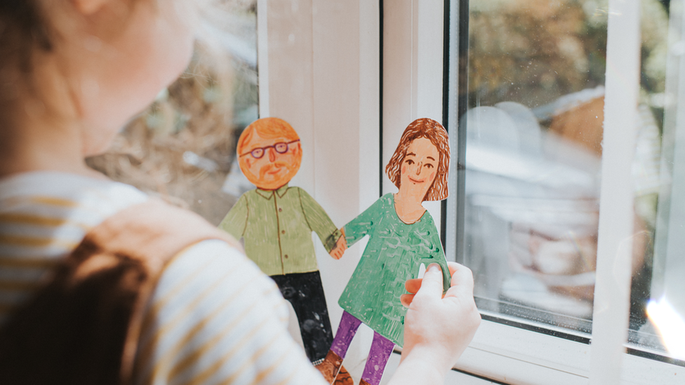 A little girl holding a paper cut out mother and father