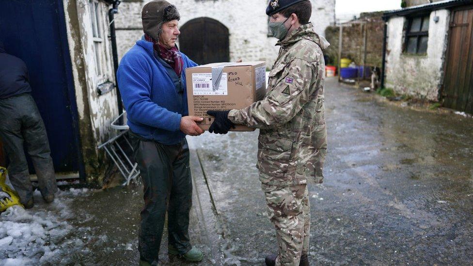 An army trooper delivers a welfare package to a farmer as welfare checks are carried out on remote properties in Teesdale, County Durham