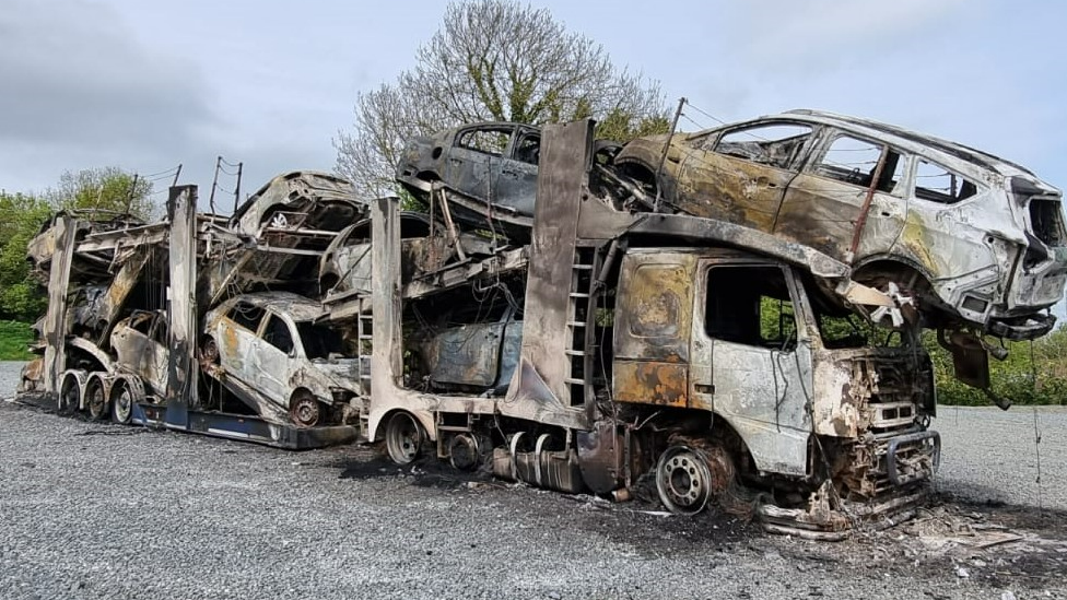 A burn-out vehicle transporter and 11 other vehicles on board