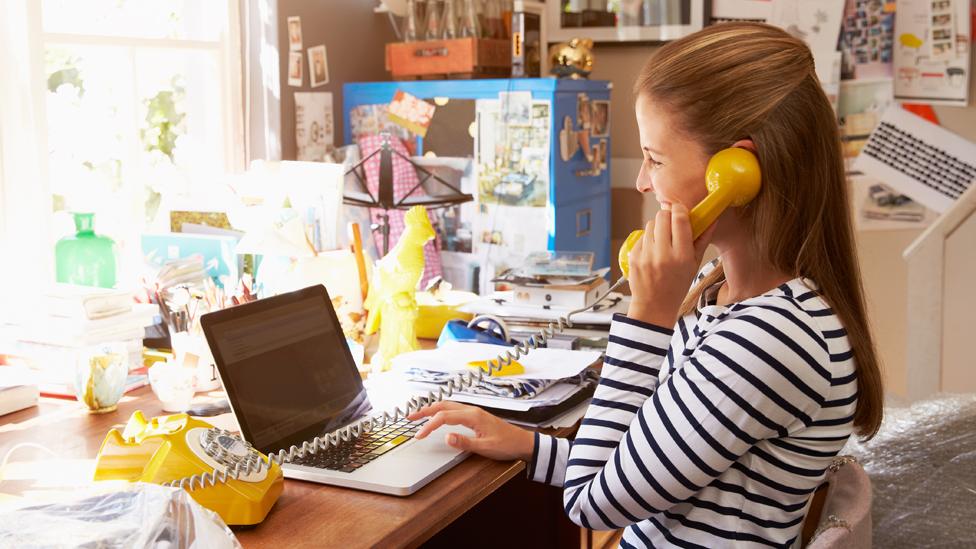 A woman works at a messy desk