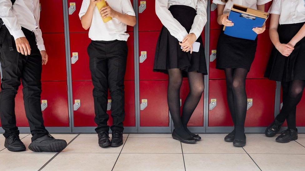 Anonymous children standing in front of lockers in uniform