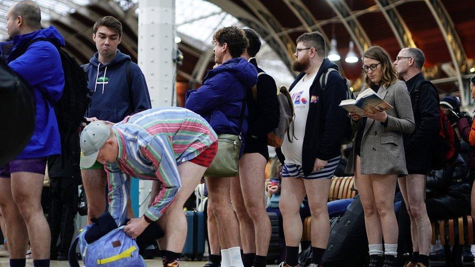 Event-goers line up with their legs on show, including one woman reading a book.