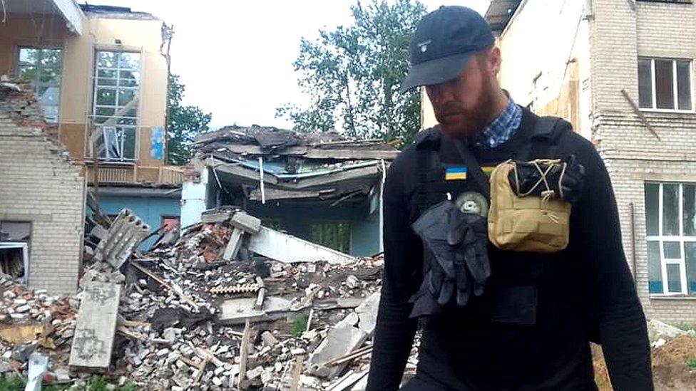 Ryan Williams by damaged building in Ukraine