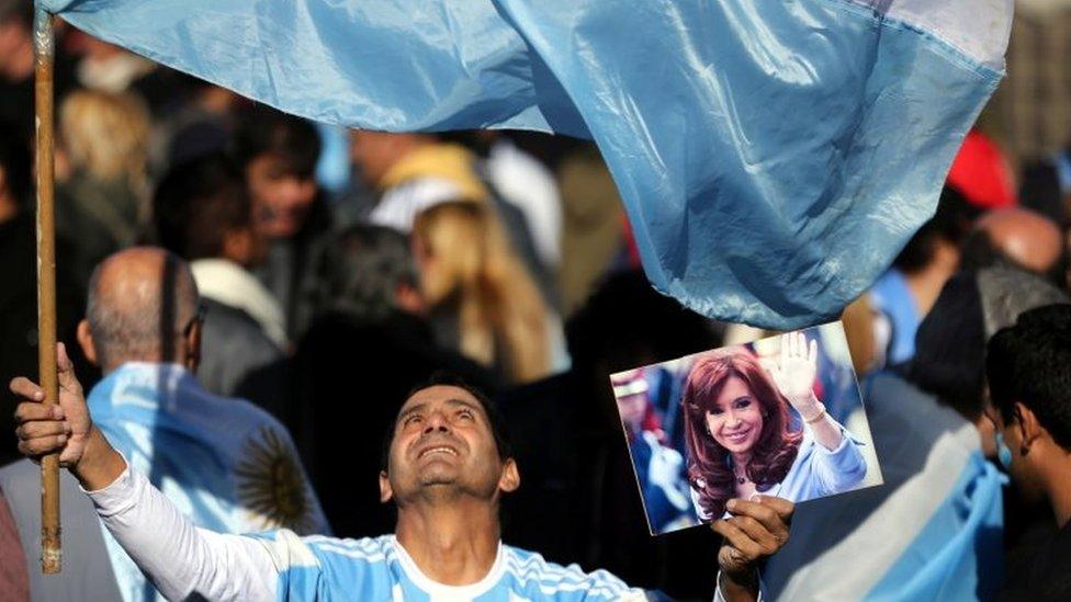 A supporter of former Argentine President Cristina Fernandez de Kirchner holds up a picture of her as he waves an Argentine flag during a rally in Buenos Aires, Argentina June 20, 2017.