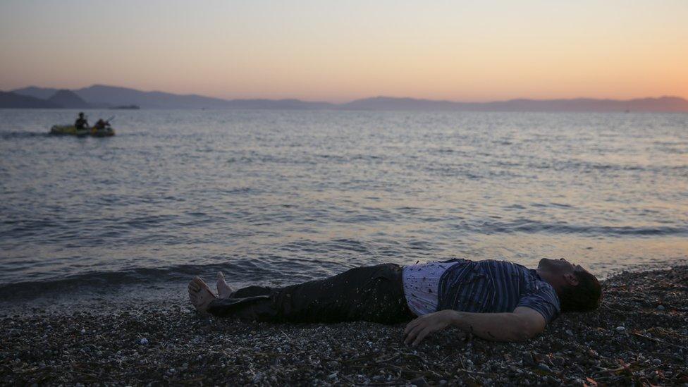 An exhausted Syrian man lays on the beach after being dragged out of the water after swimming the last 50 metres to shore as migrant families from Syria arrive in an inflatable dinghy on the beach at sunrise on the island of Kos after crossing a three mile stretch of the Aegean Sea from Turkey 28 August 2015