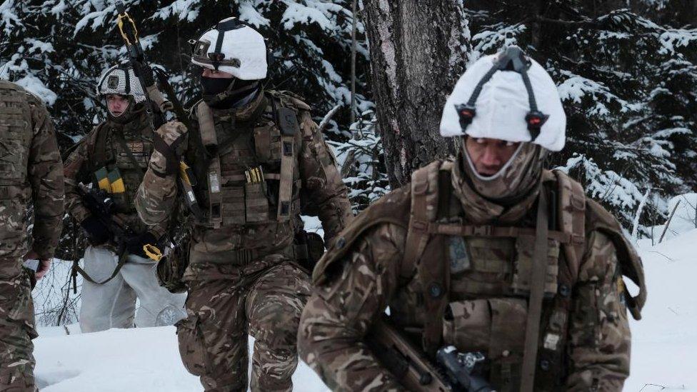 Four British Army soldiers on a military exercise in Estonia, they are in full camouflage gear in the snow and carrying rifles