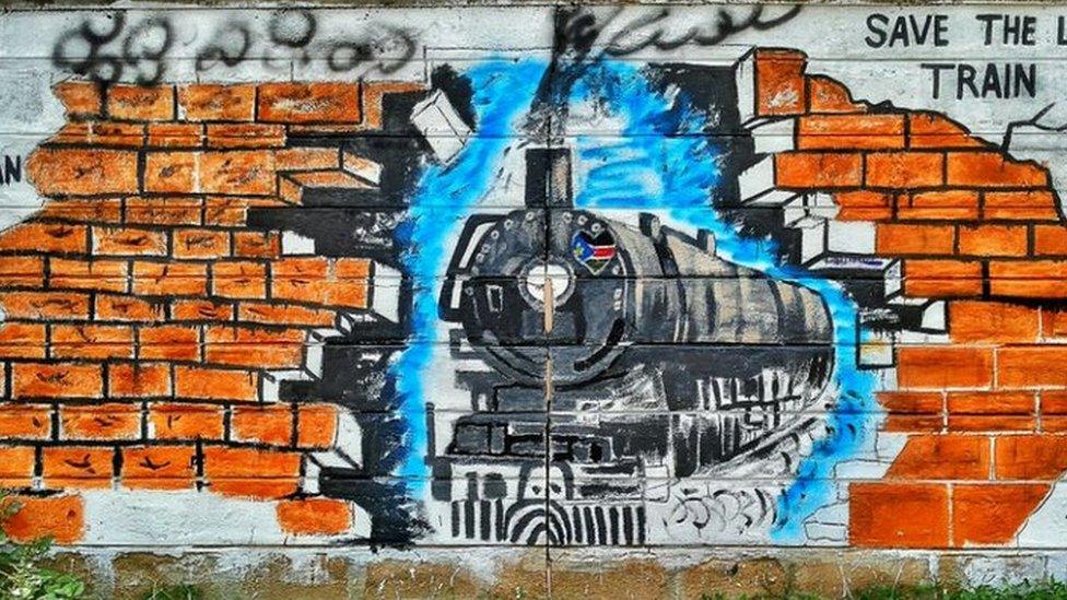 A picture of a train approaching a brick wall is painted on a wall