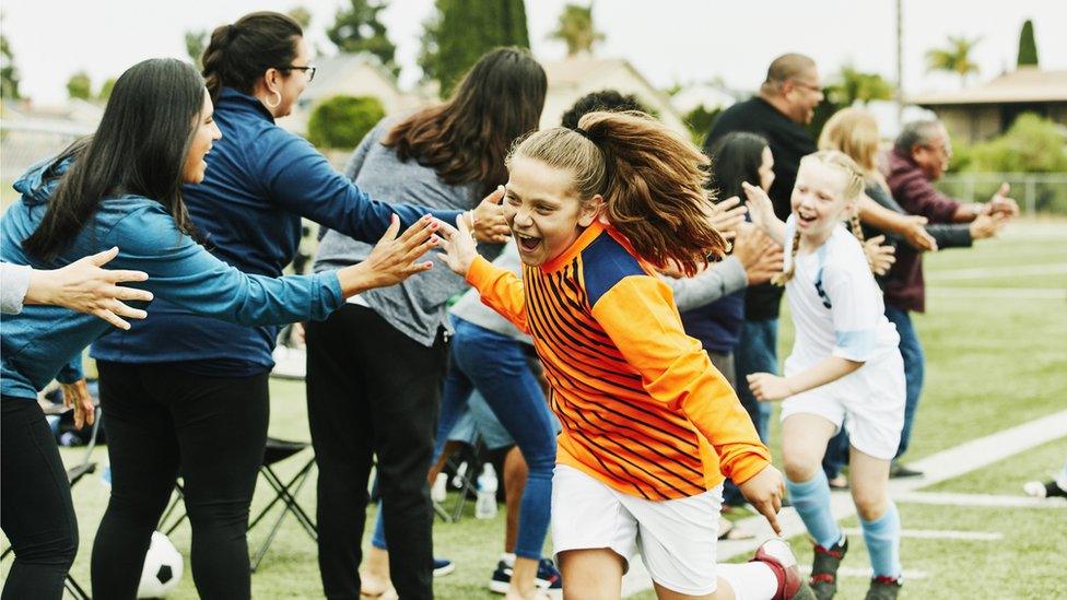 girls celebrate while playing football