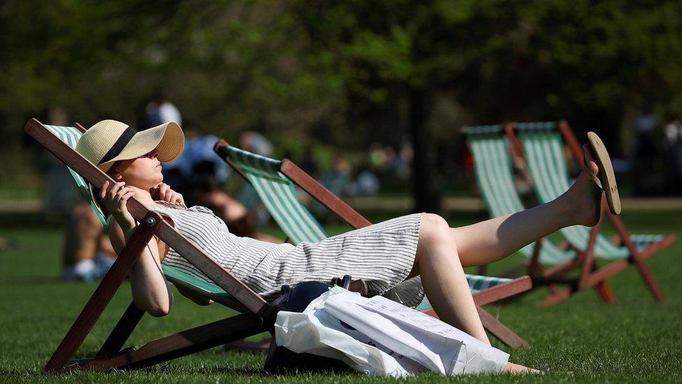 A woman lounges in the sunshine in a deckchair in St James Park, London, Britai