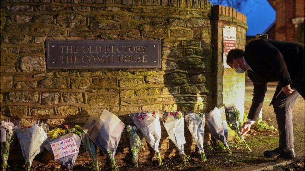 A man leaves flowers at the residence of Captain Sir Tom Moore