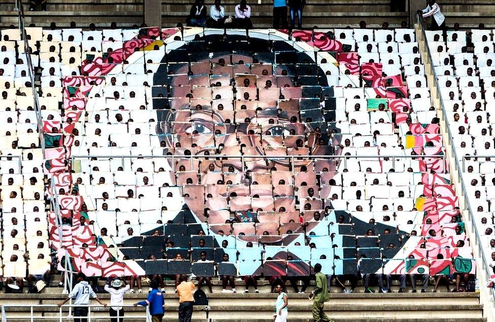 School children hold an image of Zimbabwe's President Robert Mugabe during the country's 37th Independence Day celebrations at the National Sports Stadium in Harare April 18, 2017.