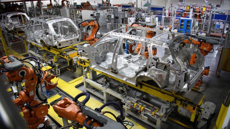 Robotic systems work on the chassis of a car during an automated stage of production at the Jaguar Land Rover factory