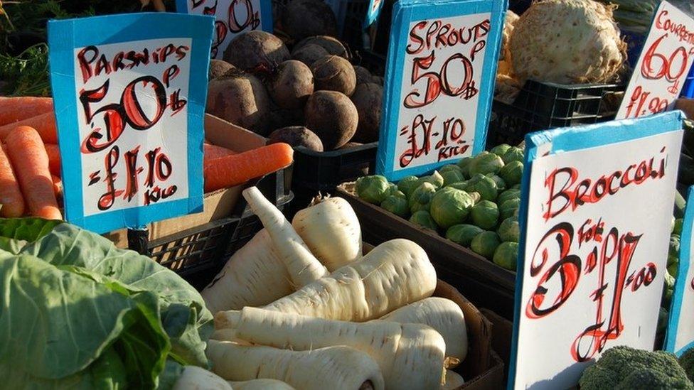 Greengrocer displaying vegetables for sale in both pounds and kilograms