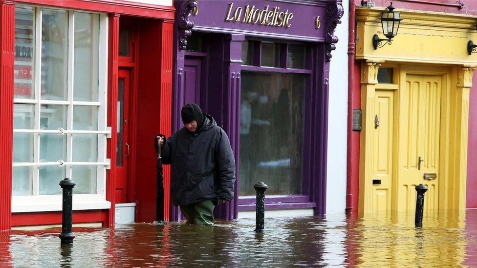 A man walks past flooded shop fronts in Bandon, Co Cork, following Storm Frank