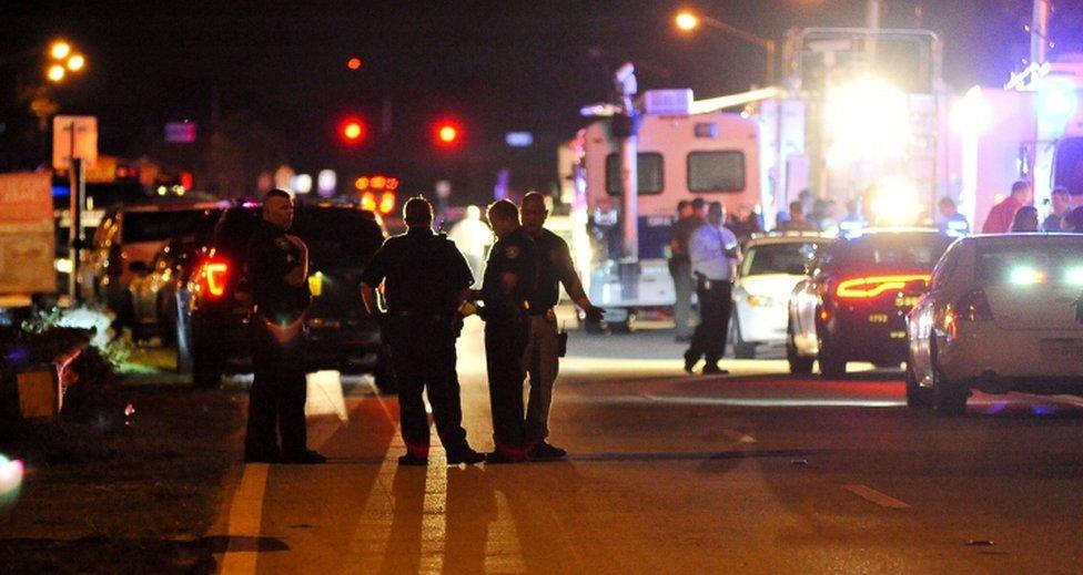 Police vehicles and officers pictured in the road after dark