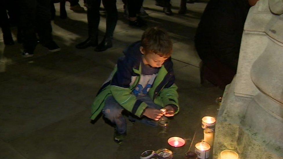 A boy lights a candle during the vigil