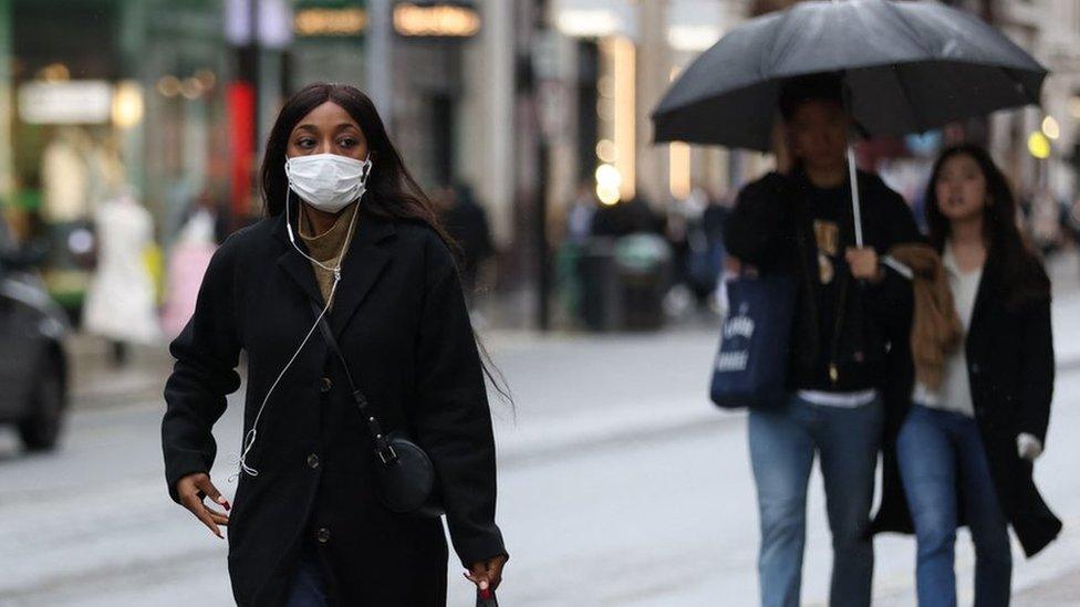 A shopper wearing a facemask to combat the spread of Covid-19, walks along Oxford Street in London on December 28, 2021.