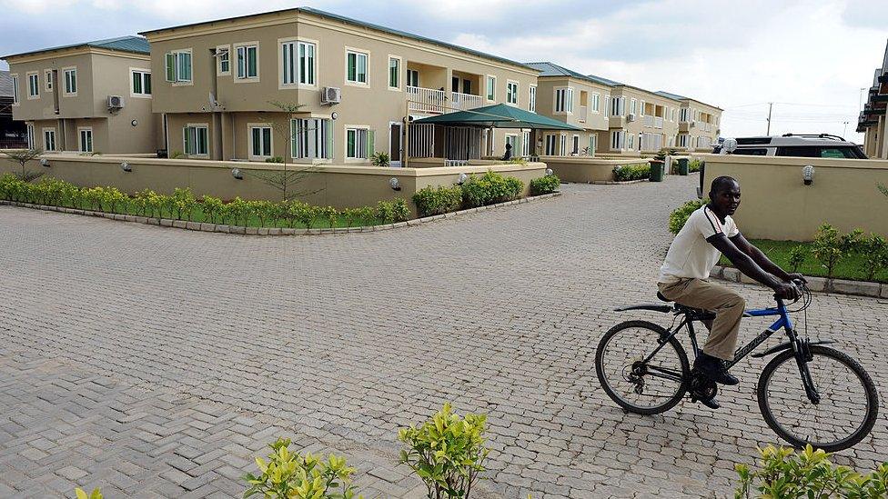 A man rides a bicycle past a block of flats