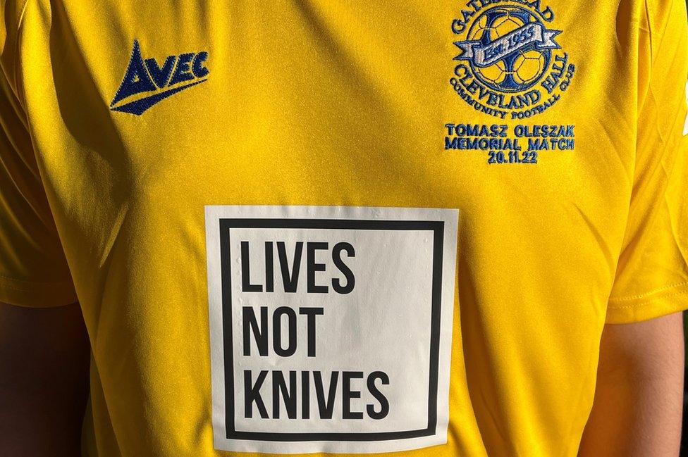 A close up of a yellow football shirt with the lives not knives message