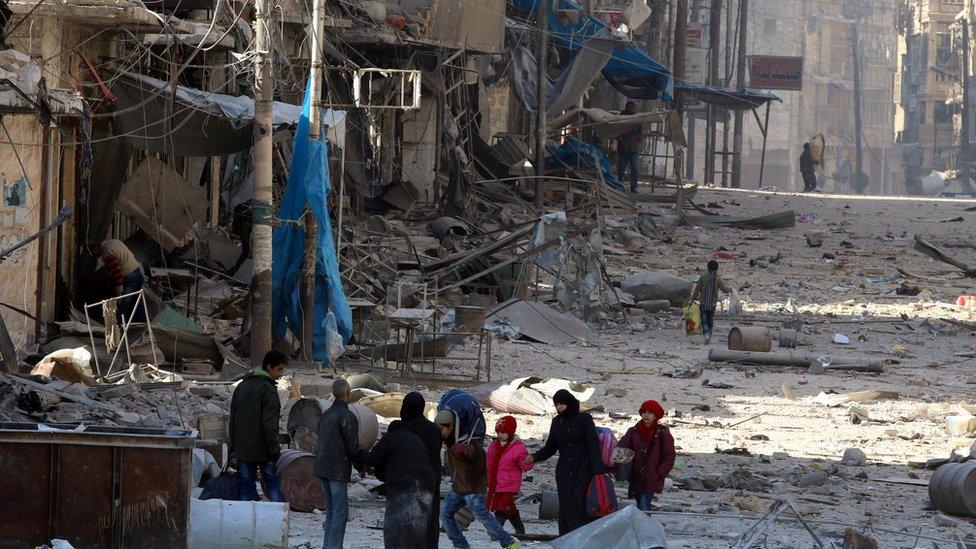 Syrians walk over rubble of damaged buildings as they flee clashes in eastern Aleppo on 28 November 2016