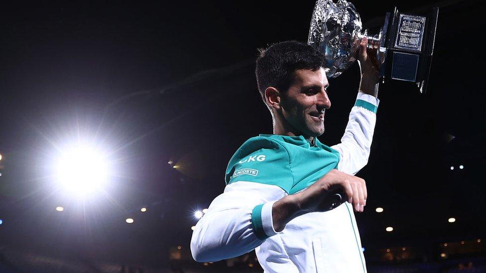 novak djokovic holds a trophy above his head