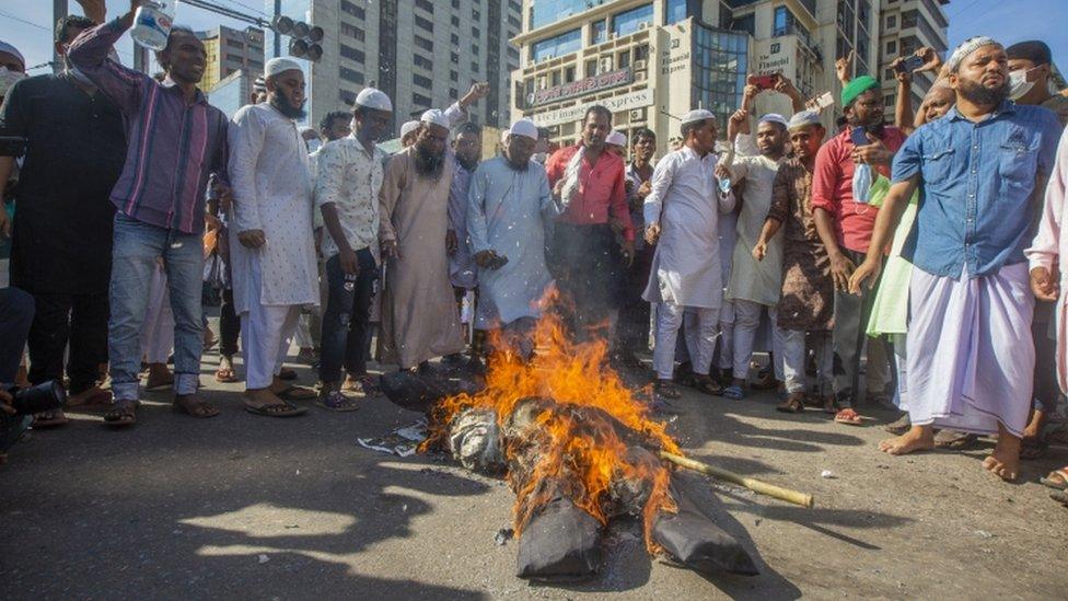 Protesters watch on as an effigy of Macron burns