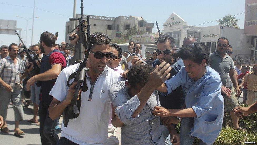 Members of the Tunisian security forces escort a man through a street in al-Sousse